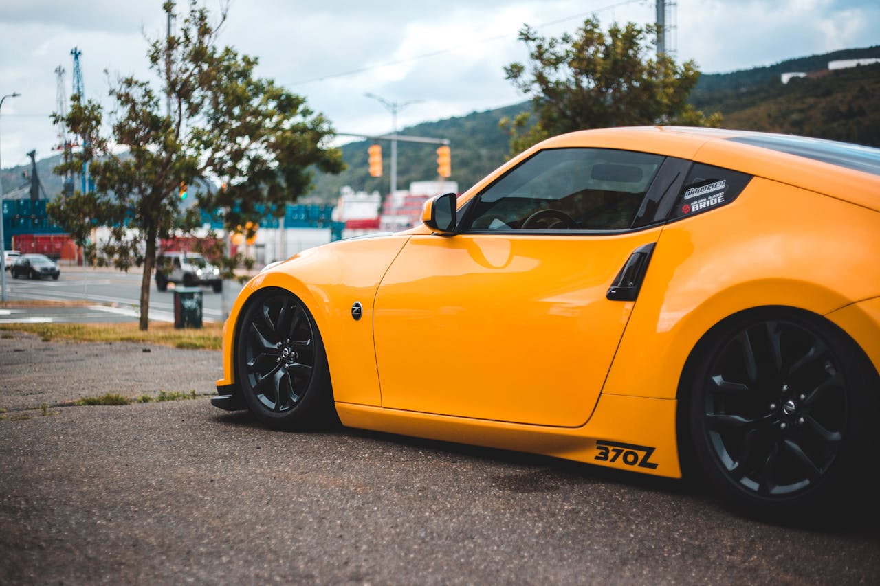 Home A yellow sports car, Nissan 370Z, parked outdoors with scenic background.